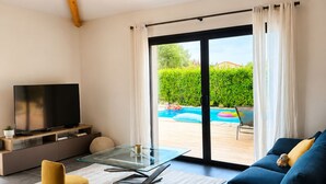Ein modernes Wohnzimmer mit Fernseher, Sofa und Glastisch.
