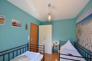 A room with two beds, a door, and a wall with a painting. - Apartment in a central location in Juliusruh, 25 m from the sandy beach with a view of the sea (Juliusruh)