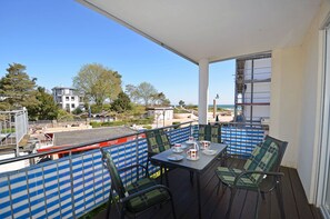 A balcony with a table and chairs, overlooking a beach and buildings. - Apartment in a central location in Juliusruh, 25 m from the sandy beach with a view of the sea (Juliusruh)