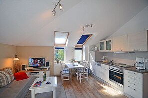 A compact living space with a kitchenette, dining area, and a television. - 2nd floor with ocean view, high-end amenities, just 30 m from the sandy beach (Baltic Sea) (Juliusruh)