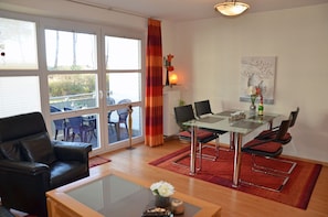 Ein Wohnzimmer mit einem Glastisch, einer Ledersofa und Blick durch große Fenster.