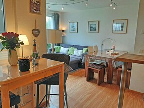 A cozy living area with a sofa, a dining table, and a coffee table. There is a lamp on the table and a vase with flowers. - Right on the beach, upscale amenities, 25 meters to the sandy beach, Wi-Fi (Juliusruh)
