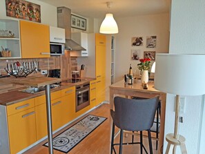 Une cuisine de taille réduite avec des meubles de couleur jaune, un plan de travail en bois et un coin repas comprenant une chaise et une table.
