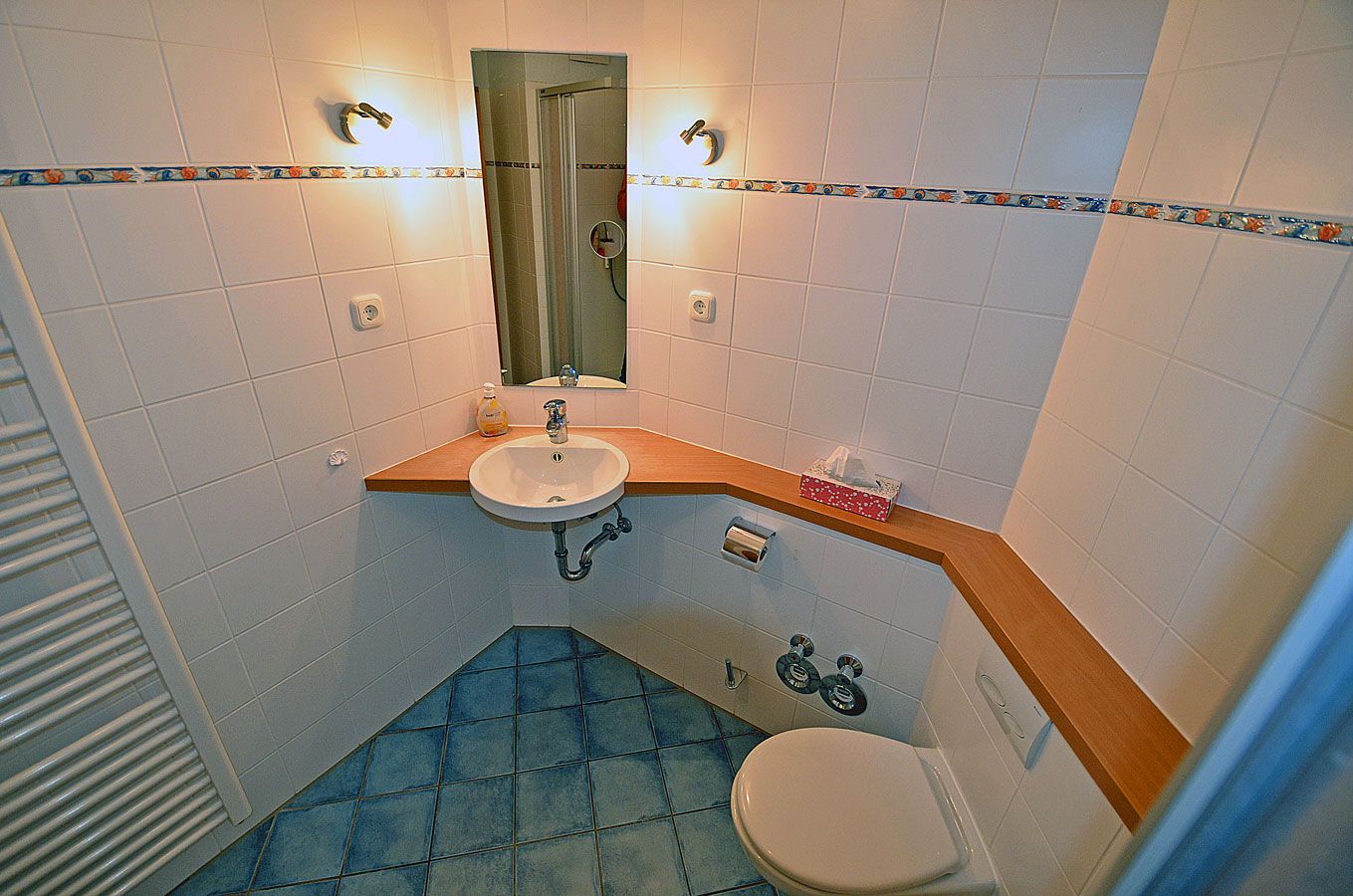 A bathroom with a sink, mirror, toilet, and shower.