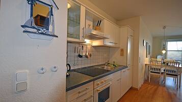 A kitchen with white cabinets, a black countertop, and a window.