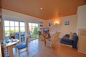 Ein geräumiges Wohnzimmer mit Fernseher, Sitzecke und Esstisch.