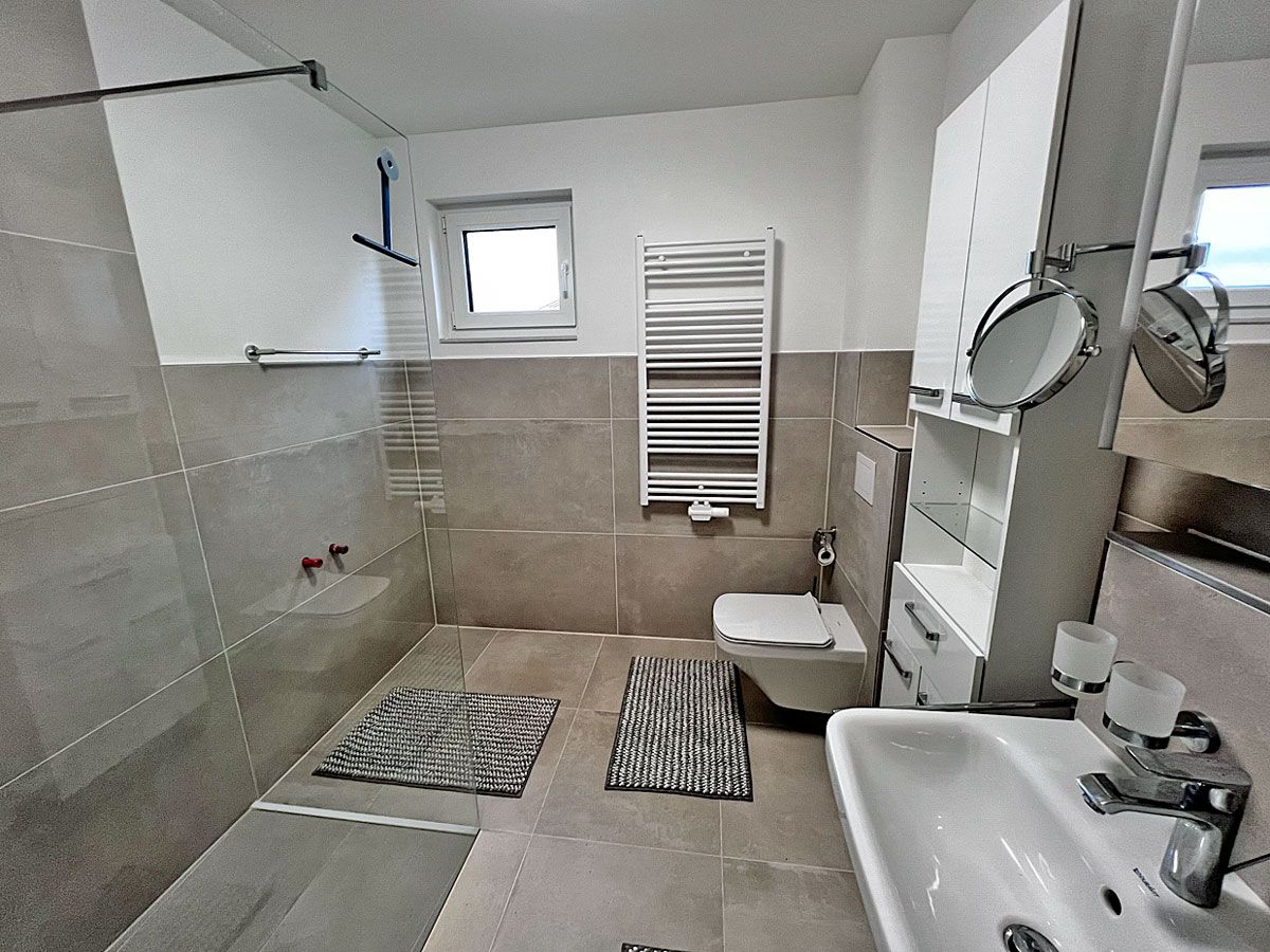 A modern bathroom with a shower, toilet, and sink.