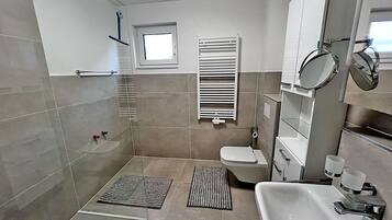 A modern bathroom with a shower, toilet, and sink.