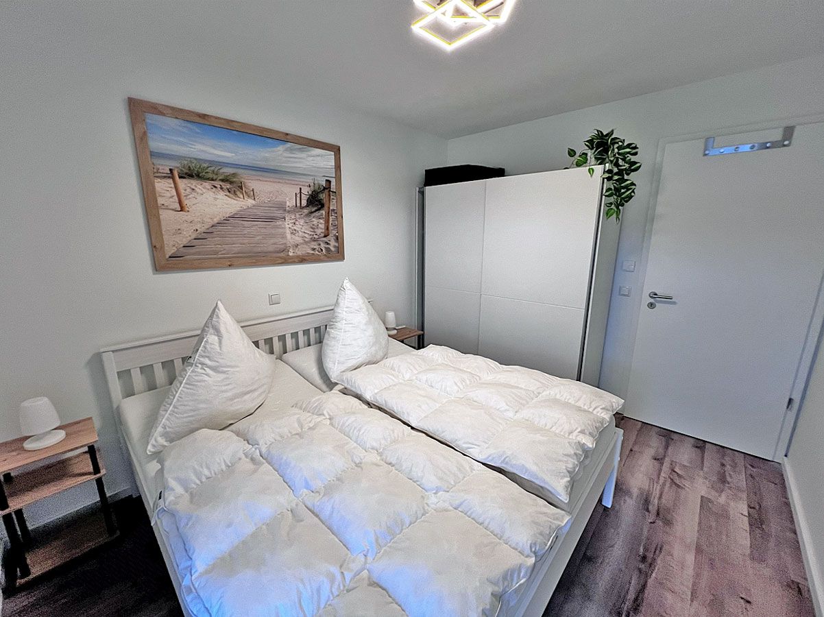 Ein Schlafzimmer mit einem Bett, einem Nachttisch, einem Kleiderschrank und einer Tür.