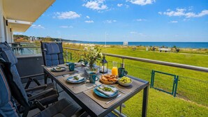 Mesa de comedor lista para el desayuno, con vistas a un paisaje costero.
