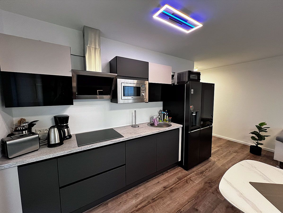 Una cocina moderna con microondas integrado, refrigerador y cafetera.