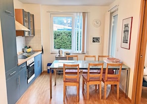 A compact kitchen with a dining area, a window with curtains, and a clock on the wall. - Right on the Baltic Sea beach, upscale amenities, 30 m from the sandy beach, Wi-Fi (Juliusruh)