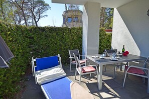 Une terrasse extérieure avec une table dressée pour deux personnes, des chaises et un canapé bleu.