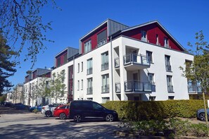 A modern apartment building with multiple balconies, parked cars, and a clear blue sky. - Right on the Baltic Sea beach, upscale amenities, 30 m from the sandy beach, Wi-Fi (Juliusruh)