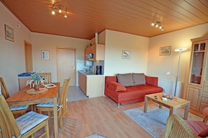 Ett kompakt bostadsutrymme med en matplats, ett litet kök och en soffa.