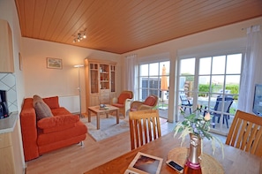 A cozy living room with a sofa, chairs, a coffee table, and a dining table with a vase of flowers. - Right on the Baltic Sea beach! Just 20 meters to the beach, patio, sleeps up to 4 people (Glowe)