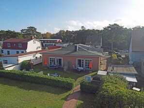 A residential property with a red-roofed house, a white building with a blue roof, and a well-maintained lawn. - Right on the Baltic Sea beach! Just 20 meters to the beach, patio, sleeps up to 4 people (Glowe)