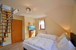Ein Schlafzimmer mit einem Bett, einem Fernseher, einem Fenster und einer Holztreppe.