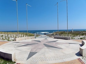 Uma praça circular com um padrão em forma de estrela, uma bicicleta e vista para o oceano.