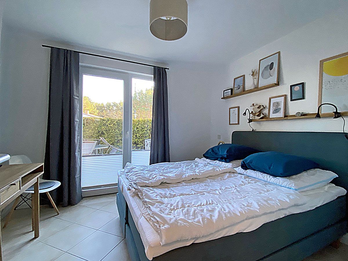 Ein Schlafzimmer mit Bett, Schreibtisch und Blick ins Freie.