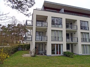 Ein mehrstöckiges Wohngebäude mit Balkonen, einer kleinen Grünfläche und einem gut sichtbaren Eingang.