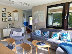 Ein modernes Wohnzimmer mit einem grauen Sofa, Holzstühlen, einem Couchtisch und einer Karte an der Wand.