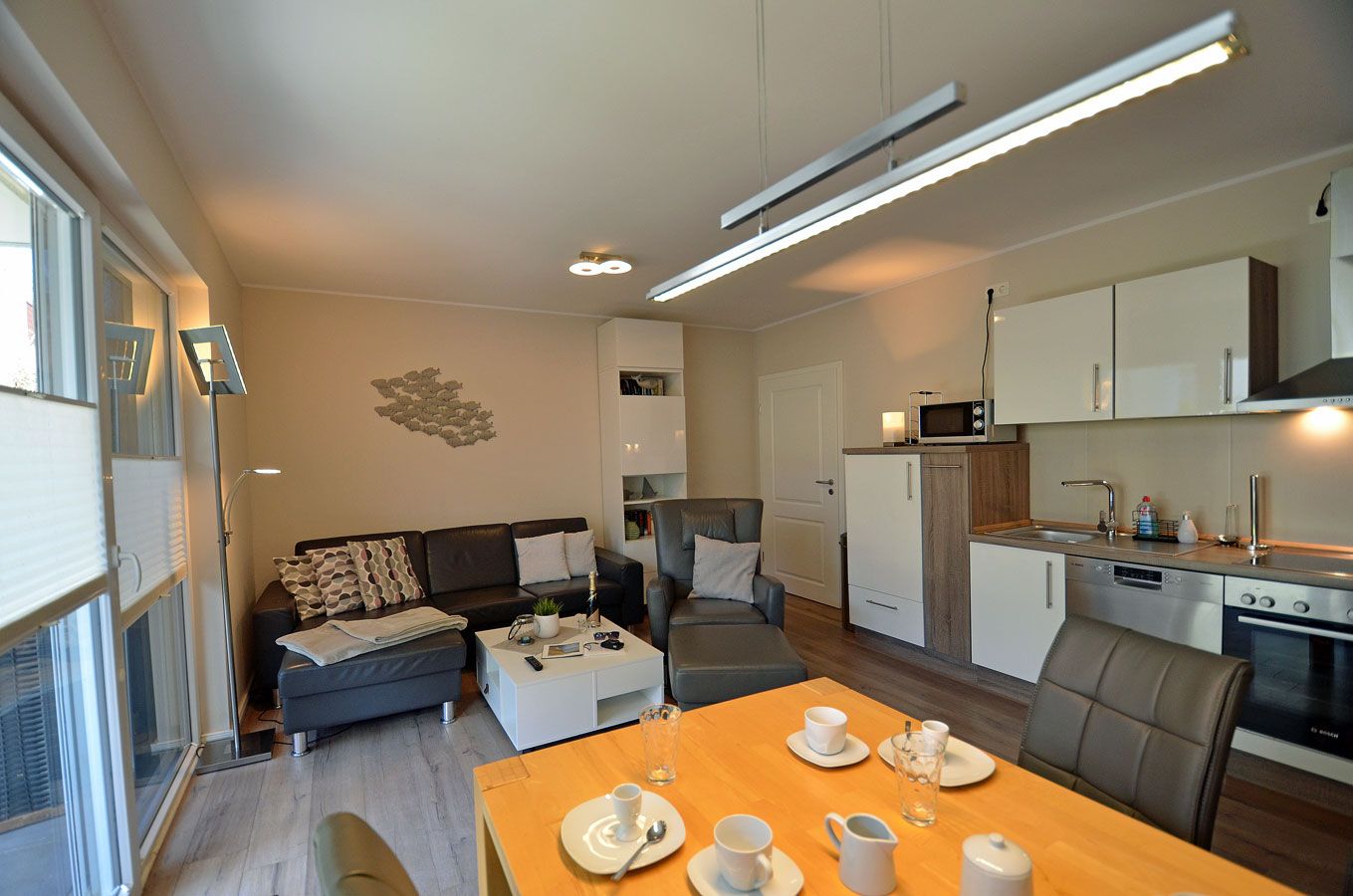 Un espacio habitable compacto con kitchenette, un comedor con mesa para dos personas y un sofá con mesita de centro.