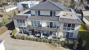 A multi-story residential building with a balcony, a paved driveway, and a fenced yard. - First floor, modern amenities, central location, about 200 m from the sandy beach (Baltic Sea) (Juliusruh)
