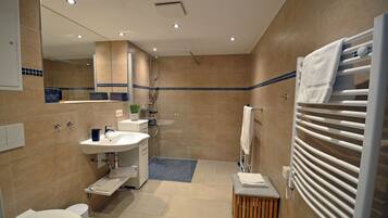 A modern bathroom with a shower, sink, toilet, and a towel rack.