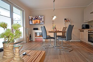 Ein modernes Wohnzimmer mit Kamin, Essbereich und Küche.
