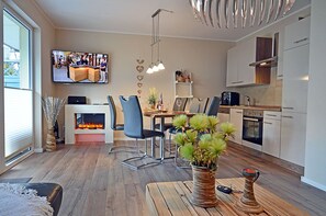 A modern kitchen with a dining area, a flat-screen TV mounted above the counter, and a fireplace. - First floor, modern amenities, central location, about 200 m from the sandy beach (Baltic Sea) (Juliusruh)