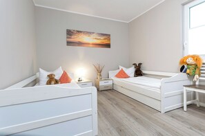 Ein Schlafzimmer mit zwei Einzelbetten, einem Nachttisch, einer Lampe, einer dekorativen Vase und einem Plüschtier.