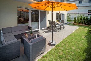 Un patio exterior con un sofá modular, una mesa de comedor y sillas.