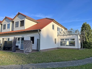 Ein zweistöckiges Haus mit rotem Ziegeldach, einer überdachten Terrasse und einer sichtbaren Garage.