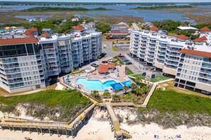 Ein Resort mit mehreren Hochhäusern, einem zentralen Poolbereich und einem Zugangsweg zum Strand.