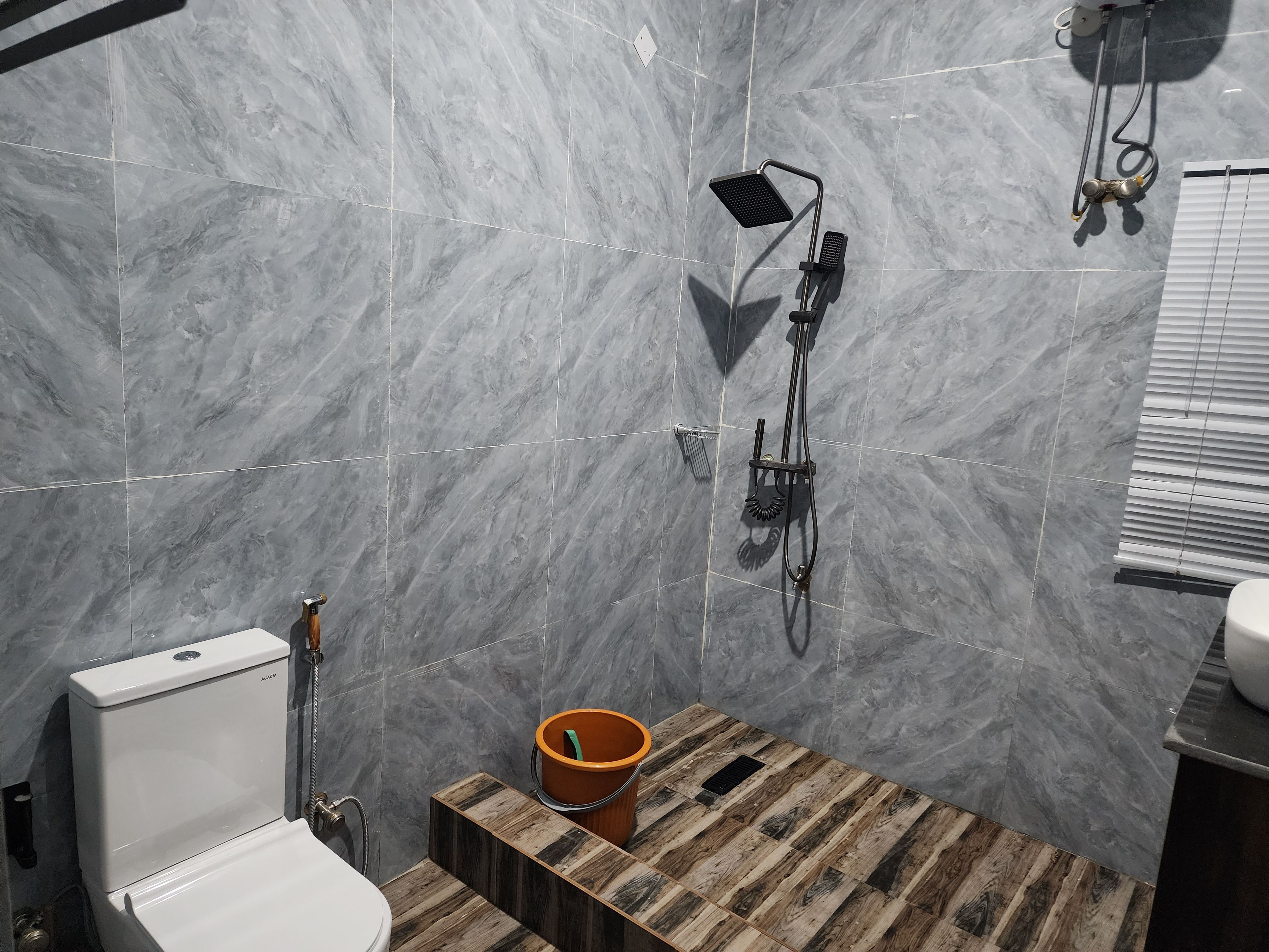 Un baño con inodoro, ducha y un balde.