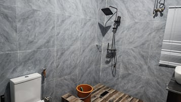 Un baño con inodoro, ducha y un balde.