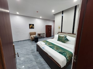 A hotel room with a bed, a chair, a small table, and a wardrobe. - Sethhotel Apartment & Suite (Asaba)