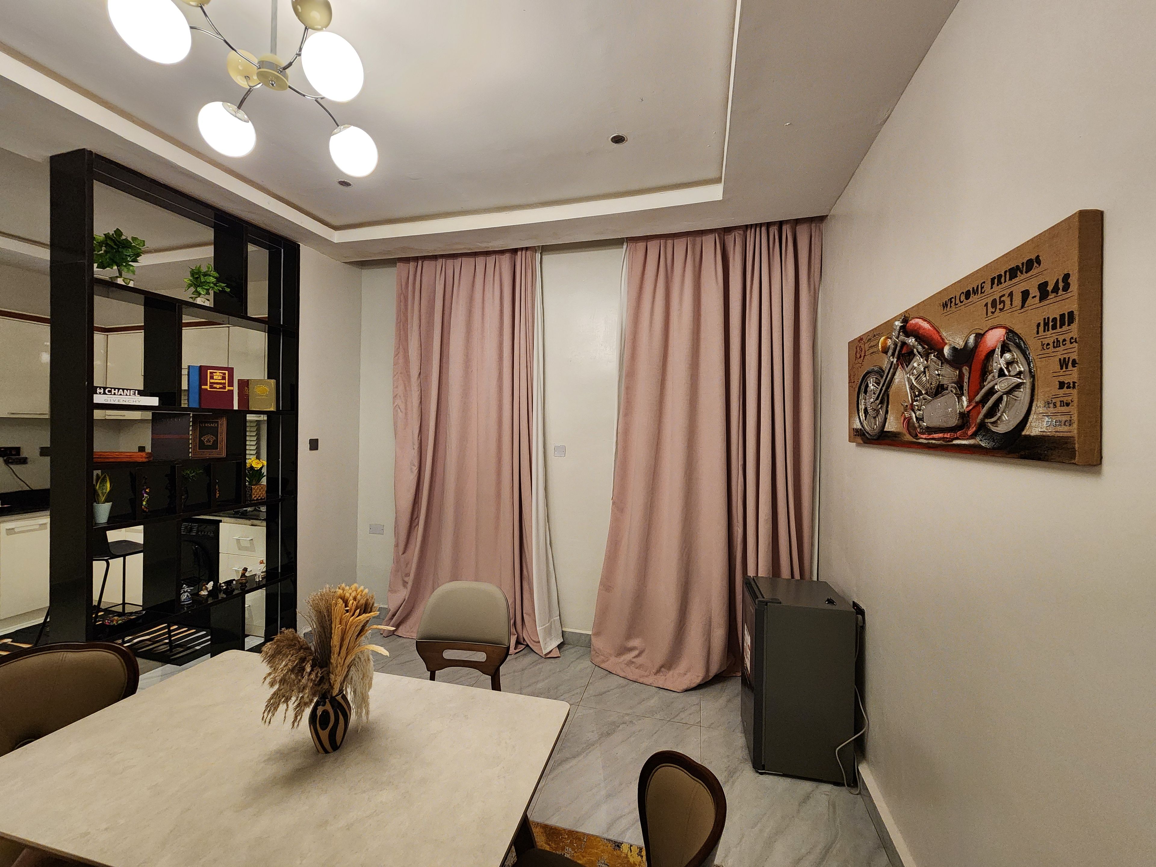 Un interior moderno con una mesa de comedor, sillas, una estantería y un altavoz montado en la pared.