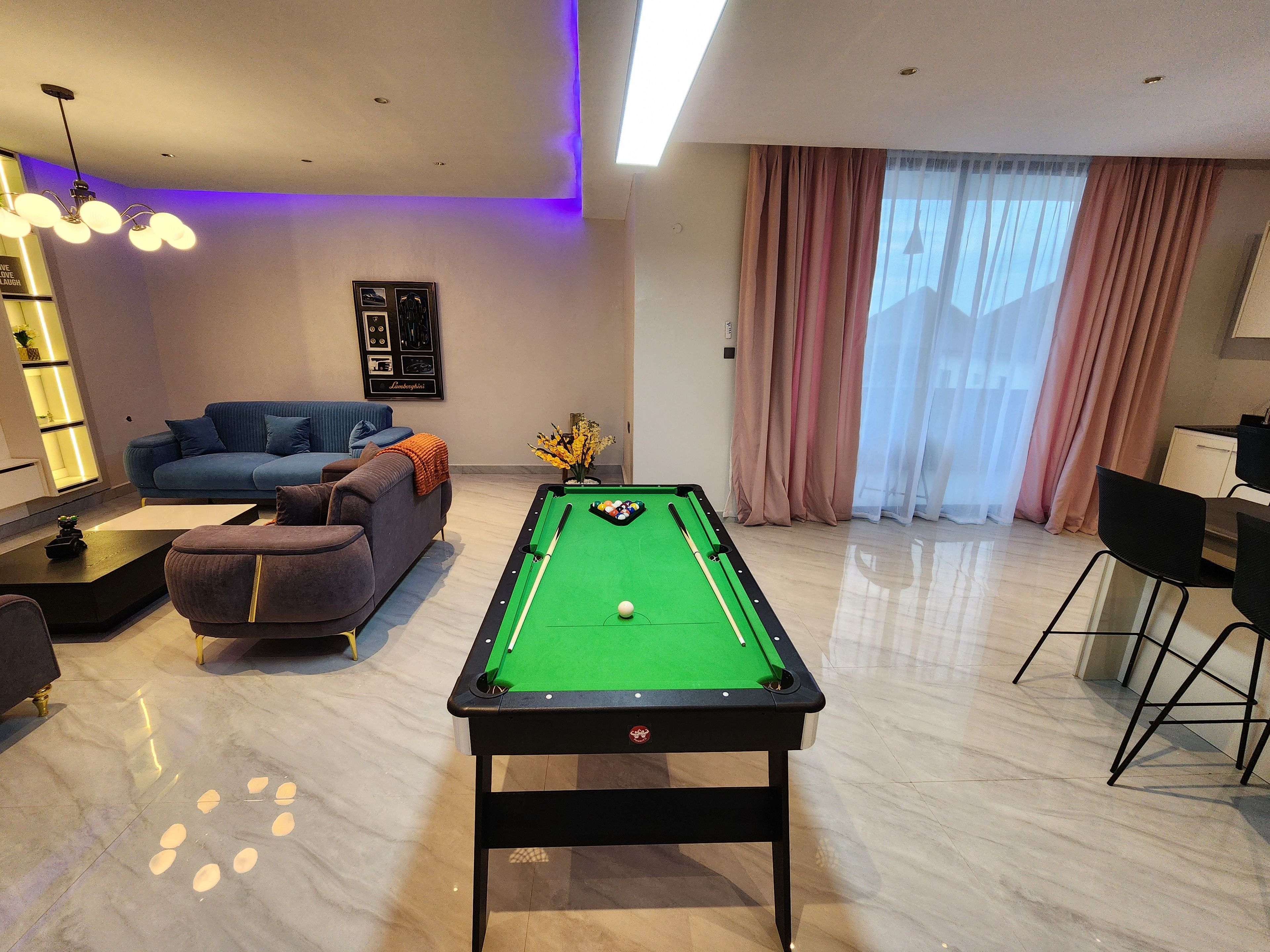 Una mesa de billar en una sala de estar moderna con un sofá y un comedor.