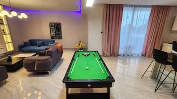Una mesa de billar en una sala de estar moderna con un sofá y un comedor.