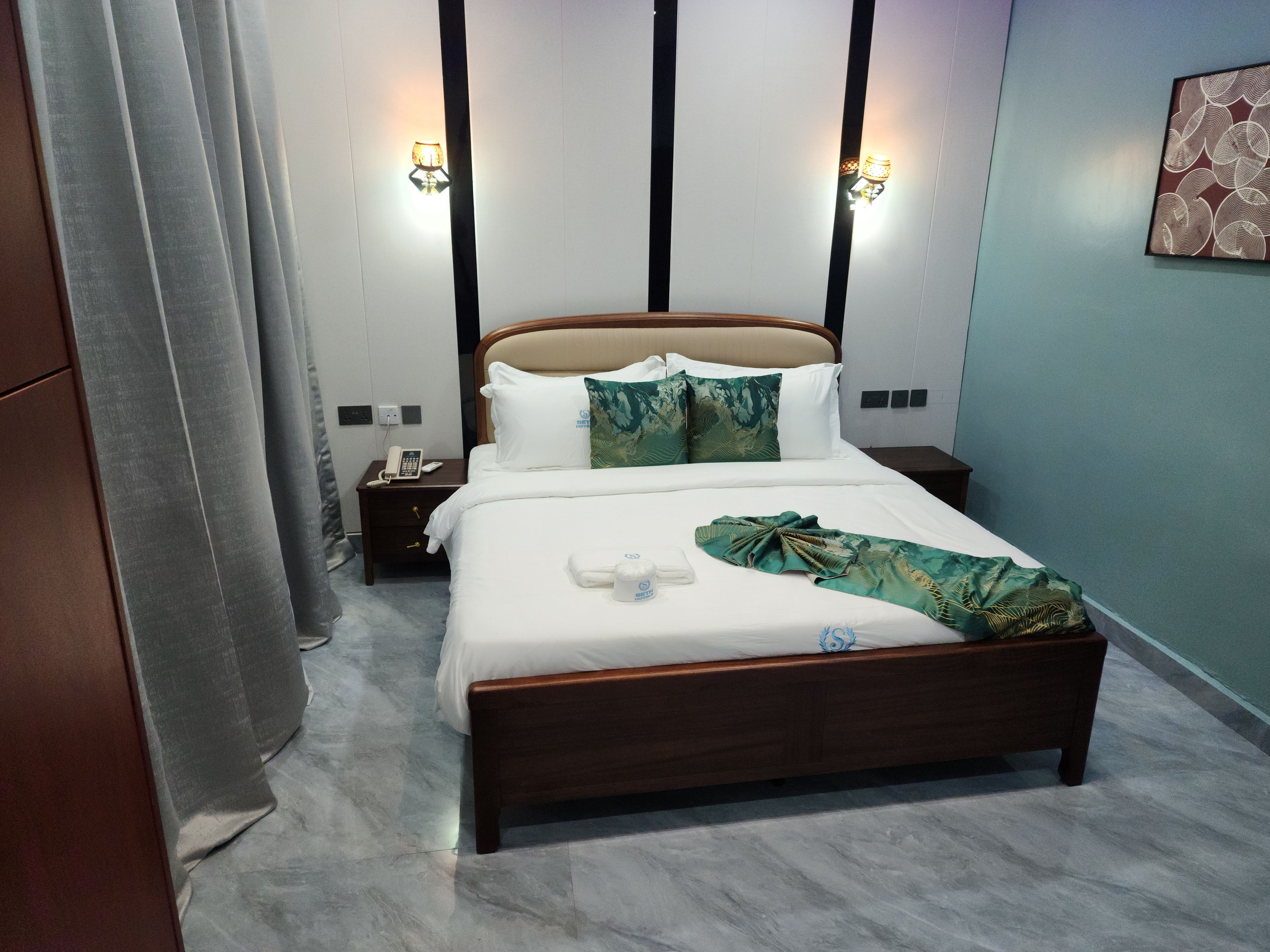 A hotel room with a bed, bedside tables, and a nightstand.