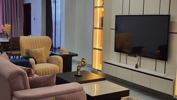 A modern living room with a sofa, armchair, coffee table, and a flat-screen TV mounted on the wall.