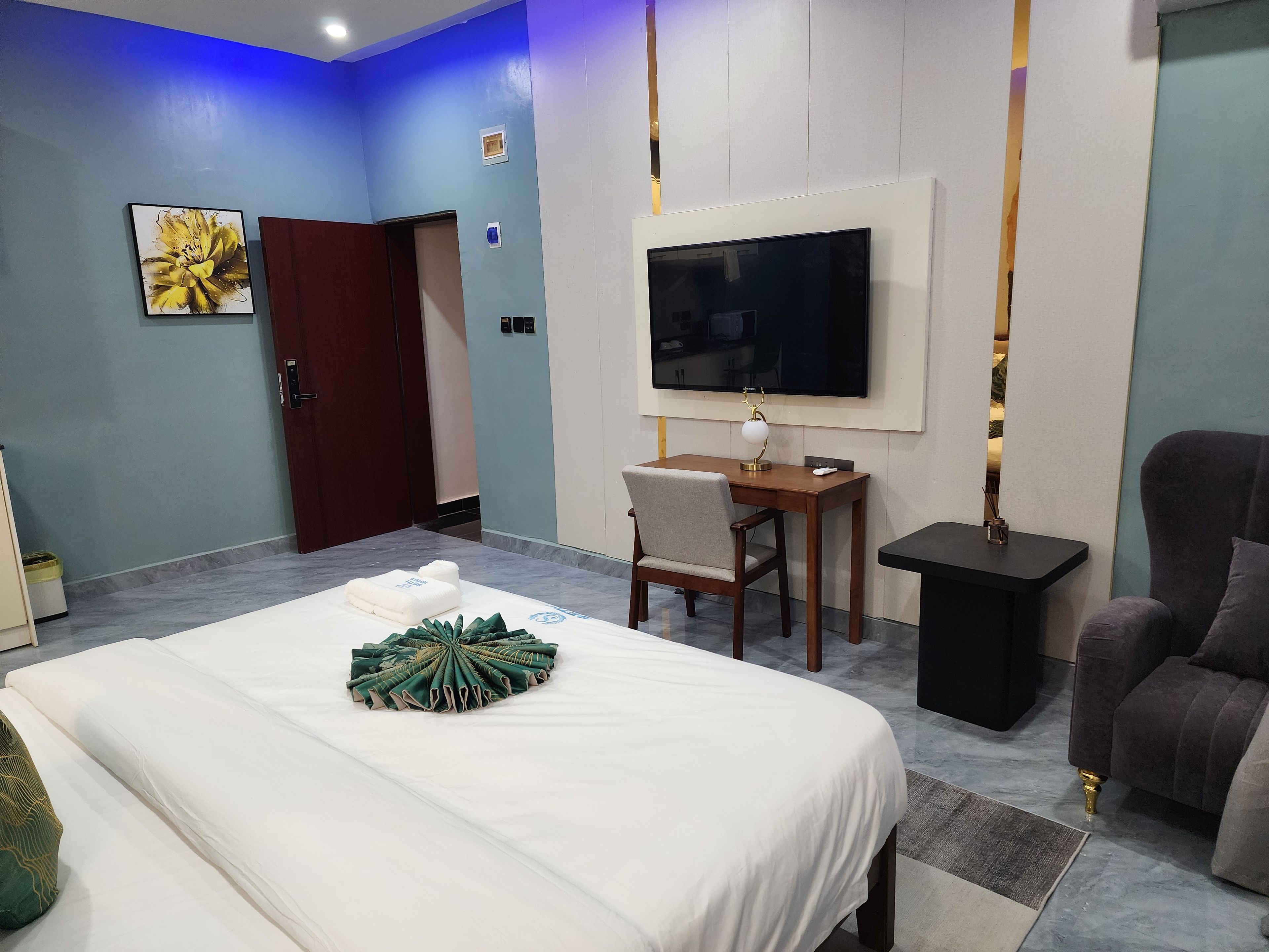 Une chambre d’hôtel avec un lit, un bureau, une chaise, une télévision et un canapé.