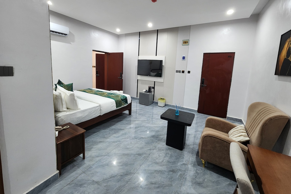 Una habitación de hotel con cama, sofá, televisión y una mesita.
