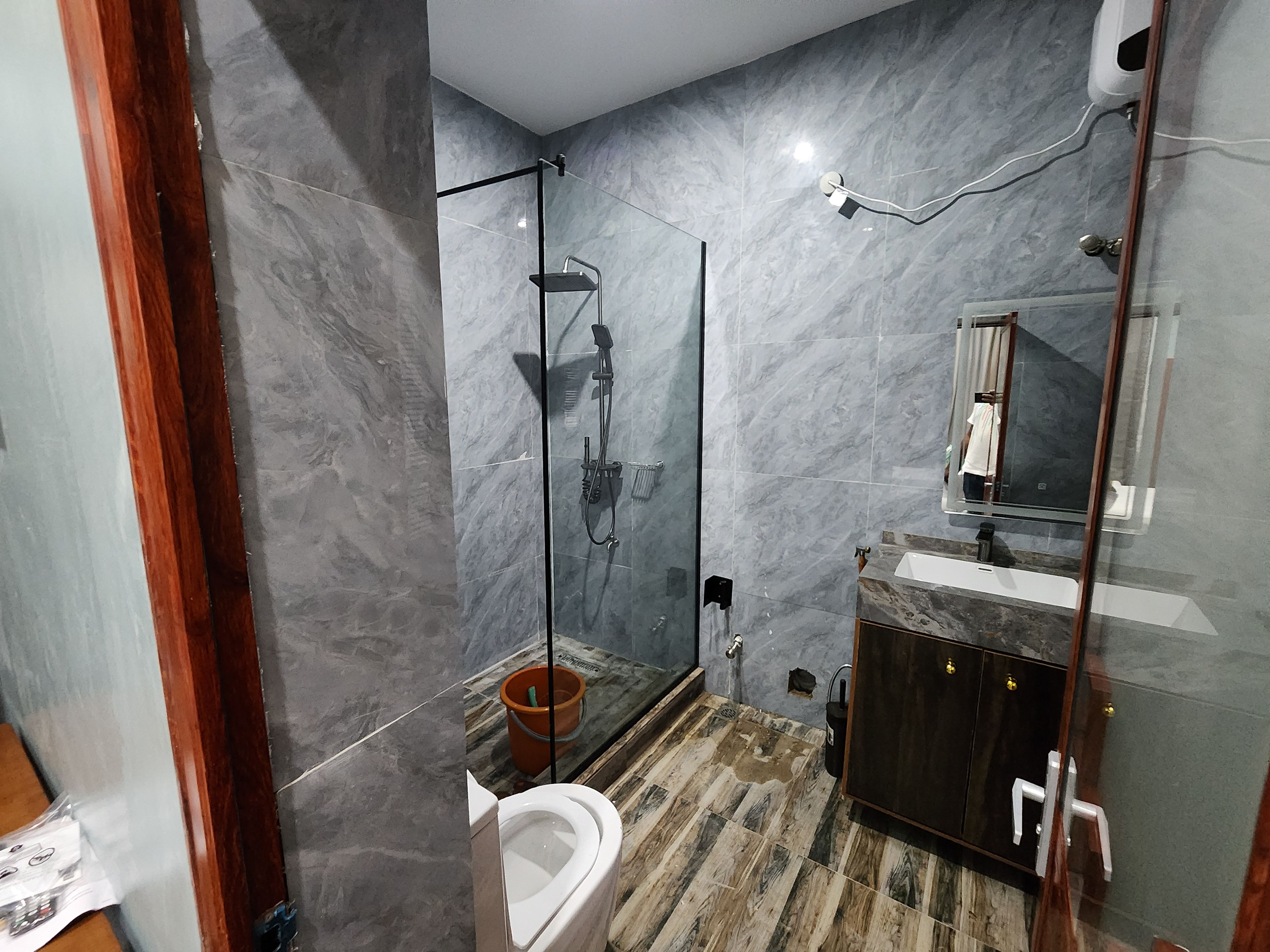 Un baño moderno con cabina de ducha de vidrio, un inodoro y un lavamanos con espejo.