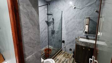 Un baño moderno con cabina de ducha de vidrio, un inodoro y un lavamanos con espejo.