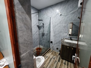 Un baño moderno con cabina de ducha de vidrio, un inodoro y un lavamanos con espejo.