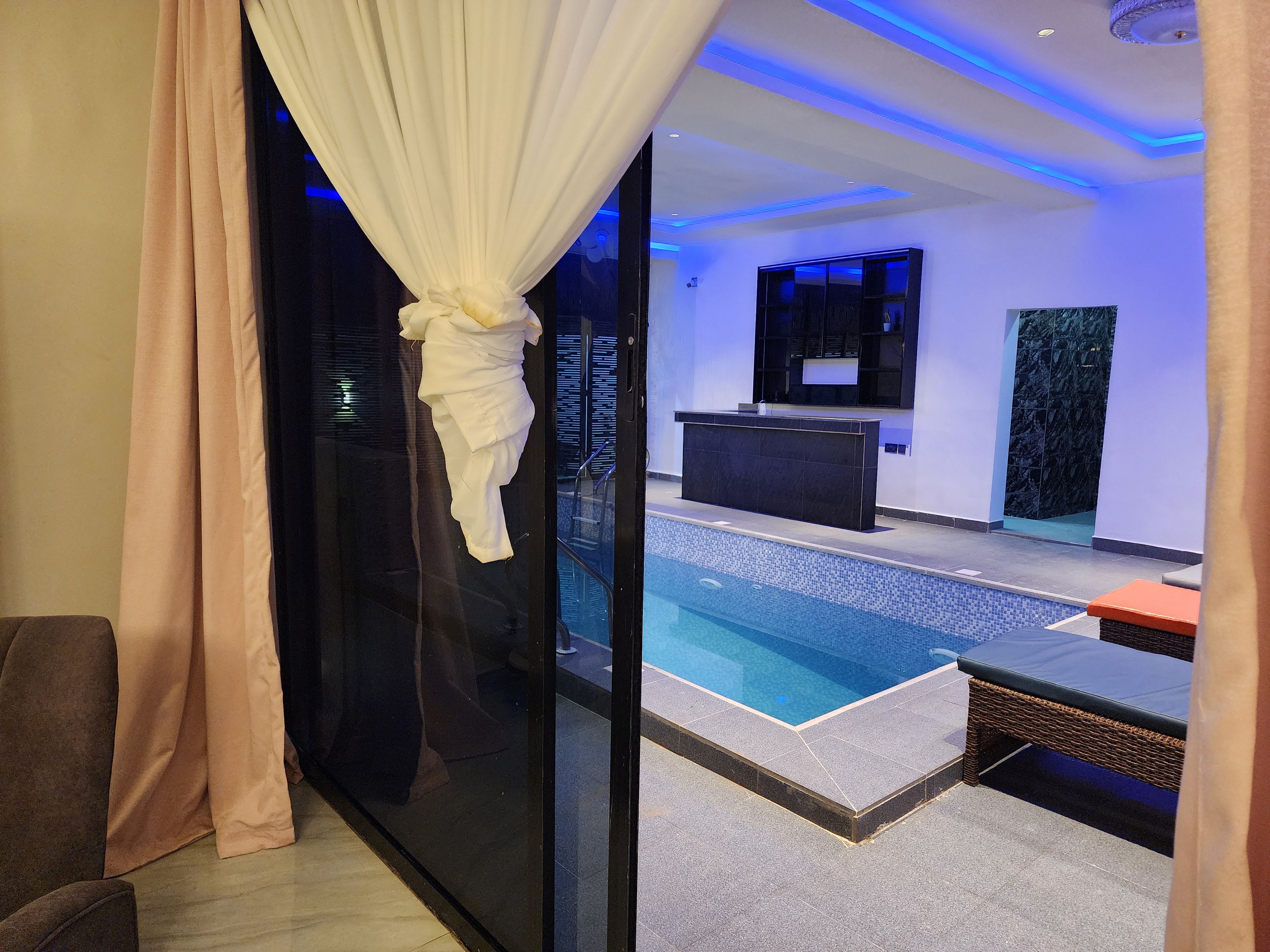 A modern indoor pool area with a reception desk, a seating area, and a glass partition.