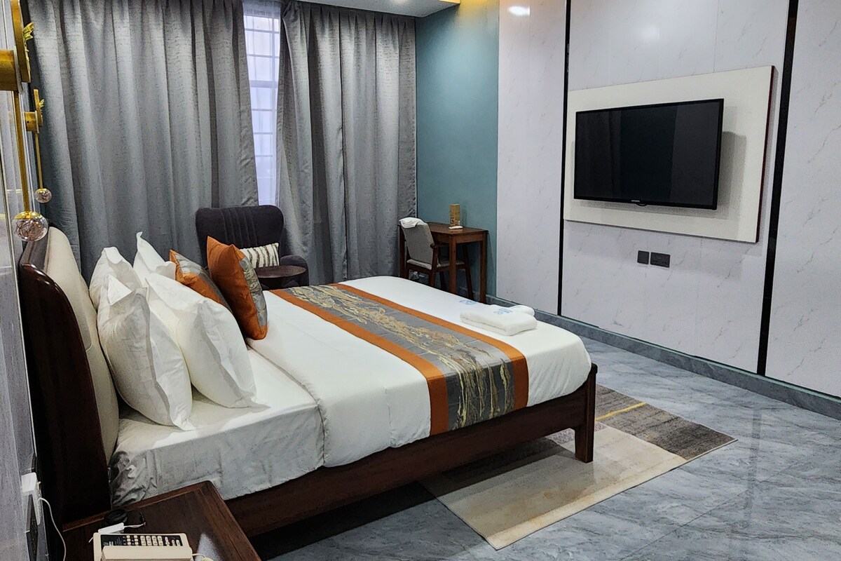Un dormitorio moderno con una cama grande, un televisor montado en la pared y un escritorio con una silla.
